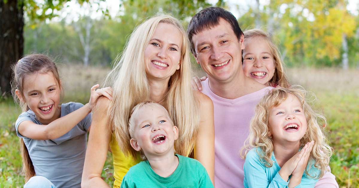 Eine Patchworkfamilie sitz zusammen auf der Wiese.